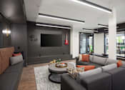 Thumbnail 9 of 25 - A modern living room with a grey couch and a flat screen TV mounted on the wall.