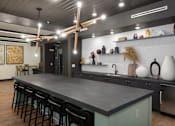 Thumbnail 10 of 25 - A modern kitchen with a long island and bar stools.