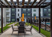 Thumbnail 18 of 25 - A patio with chairs and a table with a yellow object on it.