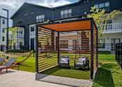 Thumbnail 16 of 25 - A patio with a hammock and chairs is surrounded by a black fence.