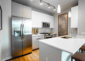 Thumbnail 4 of 26 - A modern kitchen with a white countertop and stainless steel appliances.
