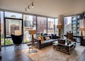 Thumbnail 2 of 26 - A living room with a view of the cityscape outside the large windows.
