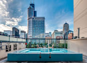 Thumbnail 18 of 26 - A swimming pool on a rooftop with a city skyline in the background.