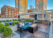 Thumbnail 19 of 26 - A rooftop patio with a fire pit and seating area.