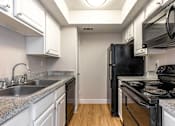 Thumbnail 3 of 19 - A kitchen with black appliances and white cabinets.