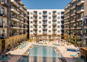 Thumbnail 11 of 16 - A large swimming pool in the middle of a courtyard surrounded by apartment buildings.