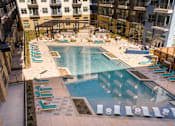Thumbnail 10 of 16 - A large swimming pool surrounded by lounge chairs and umbrellas.