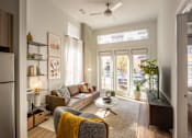 Thumbnail 1 of 16 - A modern living room with a grey sofa, a yellow throw blanket, and a ceiling fan.