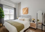 Thumbnail 5 of 16 - A bedroom with a white bed and a green quilt.