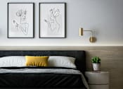 Thumbnail 2 of 3 - A bedroom with a black bed and two framed artworks on the wall.