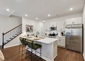 Thumbnail 8 of 16 - A kitchen with a white counter top and a stainless steel refrigerator.