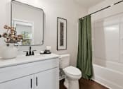 Thumbnail 16 of 16 - A white toilet sits in a bathroom next to a white sink and a white bathtub.