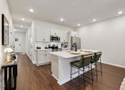 Thumbnail 9 of 16 - A modern kitchen with white cabinets and a wooden floor.