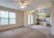 Thumbnail 13 of 32 - an empty living room with a ceiling fan and a kitchen