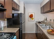Thumbnail 2 of 22 - A kitchen with brown cabinets and a black refrigerator.