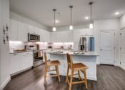 Thumbnail 2 of 17 - a kitchen with white cabinets and a large island with two stools