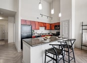 Thumbnail 26 of 35 - A kitchen with a black refrigerator and wooden cabinets.