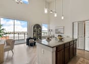 Thumbnail 27 of 35 - A modern kitchen with a large island and a balcony with a view of the sky.