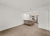 Thumbnail 2 of 24 - the living room and kitchen of an apartment with white walls and wood flooring