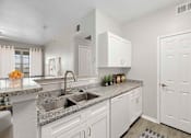 Thumbnail 12 of 14 - A kitchen with white cabinets and a granite countertop.