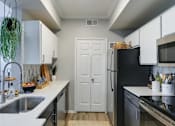 Thumbnail 7 of 34 - A kitchen with a black refrigerator and white cabinets.