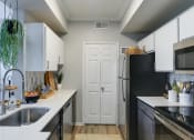 Thumbnail 3 of 29 - a kitchen with white cabinets and black and white appliances