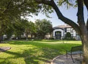 Thumbnail 14 of 29 - a park with trees and a bench in front of a building