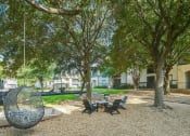 Thumbnail 10 of 29 - a park with trees and a table and chairs in a courtyard