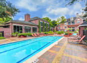Thumbnail 1 of 30 - A swimming pool with a brick building in the background.
