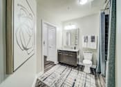Thumbnail 10 of 26 - A bathroom with a toilet, sink, and mirror.