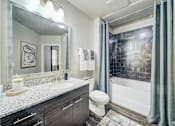 Thumbnail 7 of 26 - A bathroom with a white toilet, a sink, and a shower.