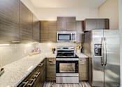 Thumbnail 2 of 26 - A modern kitchen with a stainless steel refrigerator and oven.
