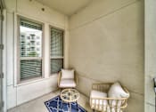 Thumbnail 14 of 26 - A chair and a basket with pillows are on a balcony.