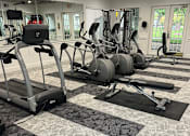 Thumbnail 16 of 29 - A gym with treadmills, exercise bikes, and weights.