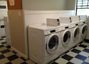 Thumbnail 21 of 22 - A row of white front load washing machines in a laundromat.