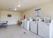 Thumbnail 21 of 23 - A laundry room with washers and dryers and a table.