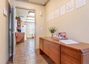 Thumbnail 15 of 23 - A hallway with a wooden desk and a wall of papers.