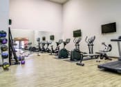 Thumbnail 9 of 25 - a large fitness room filled with cardio equipment and a tv