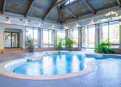 Thumbnail 5 of 25 - a large indoor swimming pool with glass doors and a wood ceiling