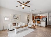 Thumbnail 19 of 35 - A living room with a white couch and a ceiling fan.