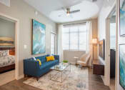 Thumbnail 12 of 45 - a living room with a blue couch and a ceiling fan