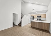 Thumbnail 6 of 24 - the living room and kitchen of an apartment with white walls and wood flooring