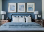 Thumbnail 11 of 43 - a bedroom with blue walls and three paintings on the wall