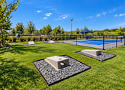 Thumbnail 17 of 30 - A backyard with a tennis court and two concrete objects on gravel.