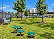 Thumbnail 19 of 30 - A sunny day at the park with green tables and a bench.