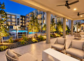 Thumbnail 12 of 30 - A patio with chairs and a table is illuminated by lights.