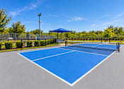 Thumbnail 18 of 30 - A blue tennis court with white lines and a white canopy.