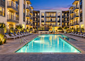 Thumbnail 6 of 30 - A swimming pool in front of a building with lounge chairs around it.