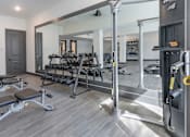 Thumbnail 31 of 48 - A gym with a variety of equipment including a bench press, a squat rack, and a mirror.