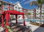 Thumbnail 43 of 48 - A pool area with a red canopy and lounge chairs.